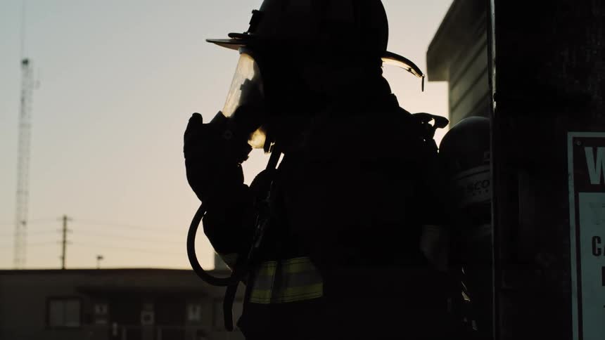 A firefighter in full gear walks away from a building