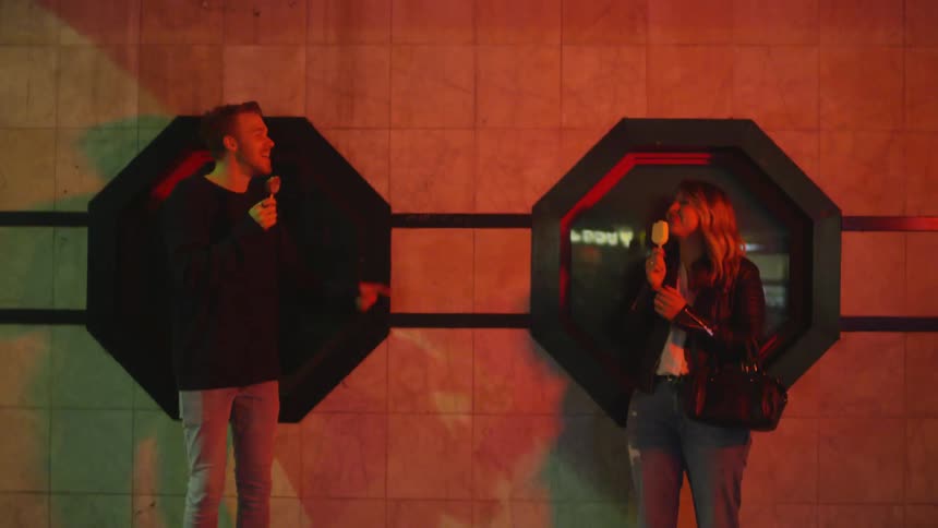 A man and woman eat ice cream outside at night