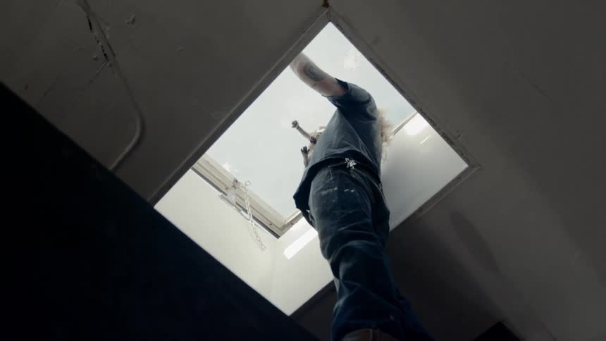 A man holds a dog as he looks out of a skylight