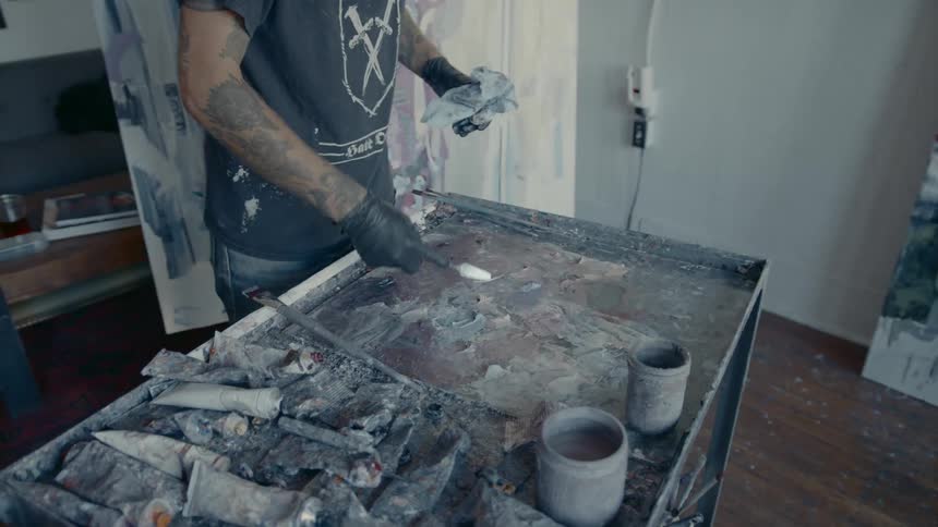 A young man is mixing paints while painting in an art studio