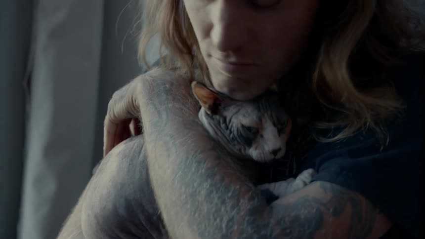 A man holds his cat and rubs his head