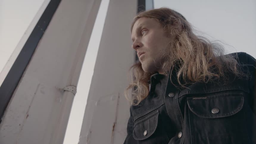 A man looks out a window with a sad look on his face