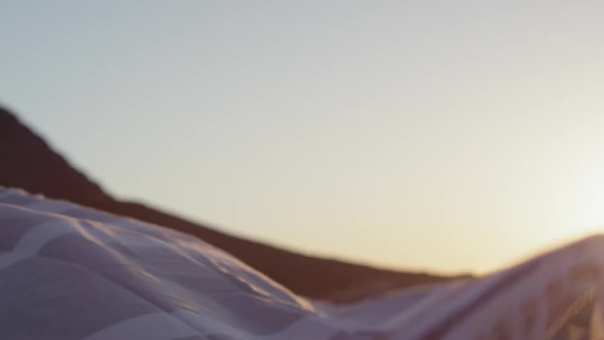 A man unfurls a large beach blanket