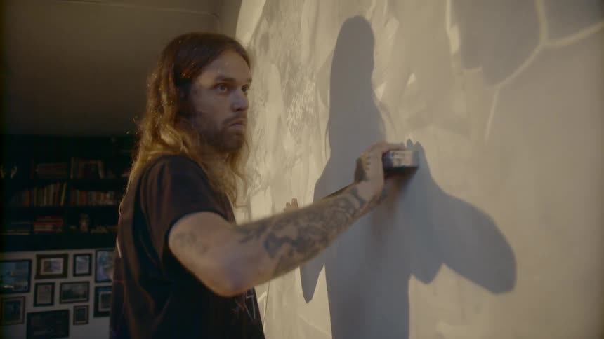 A man is measuring the wall in the dark room