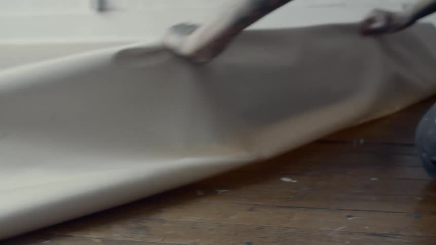 Man unrolls large canvas on floor