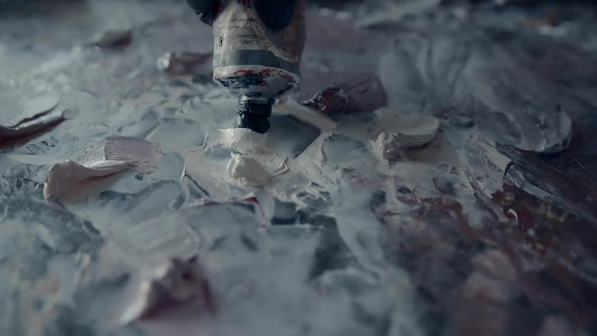 A artist applies a dot of dark paint atop a blend of lighter colored paint