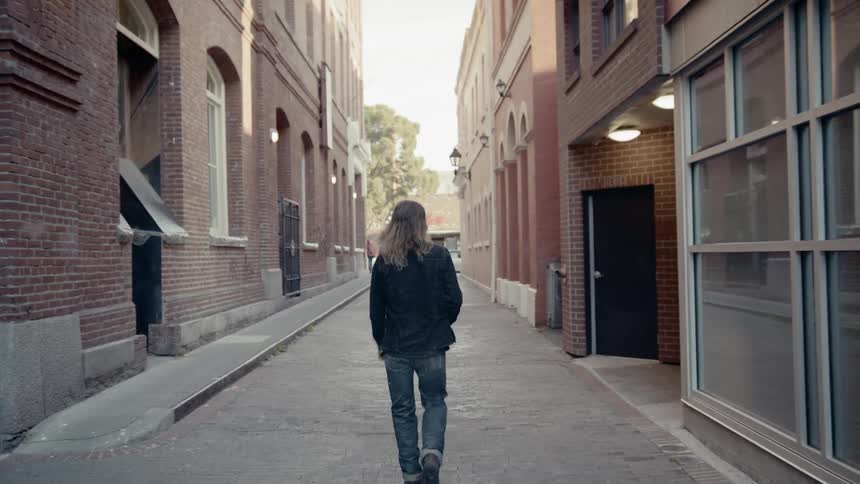Long haired blonde man walks down the street in the city
