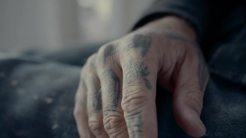 A tattoo covered hand sits in a persons lap