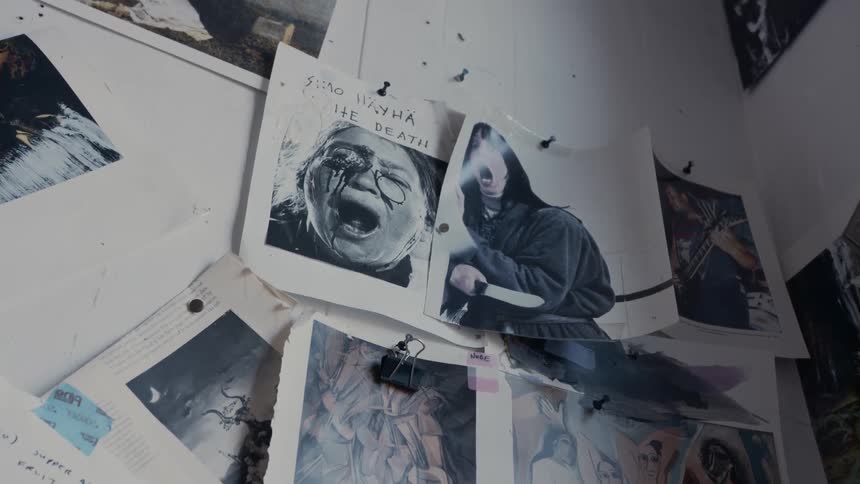 Photographs from horror films and scary paintings are tacked on a white wall