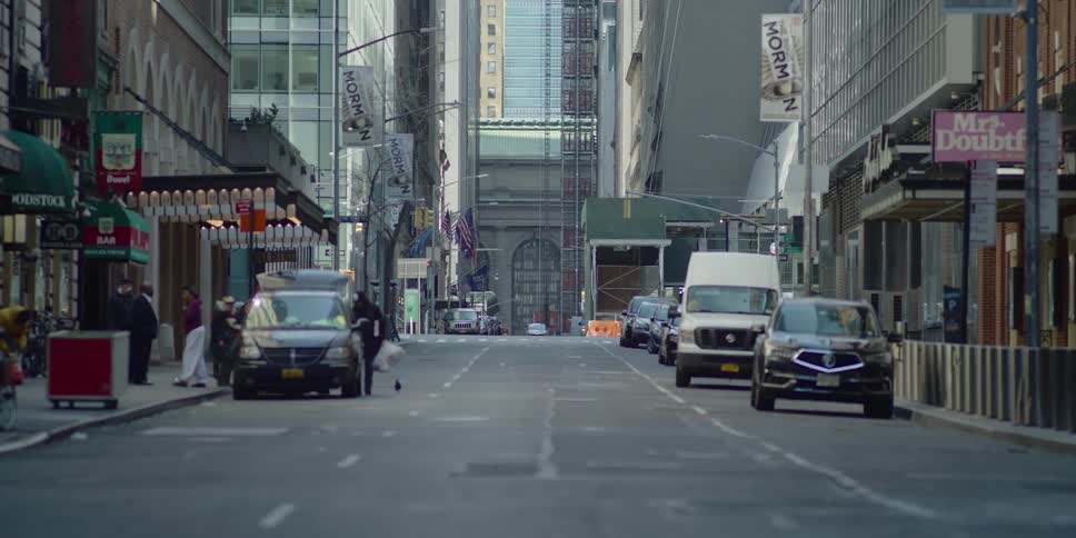 A number of vehicles are parked along the sides of a downtown street