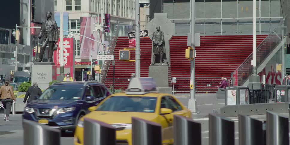 People walk in duffy square as cars and cabs drive by
