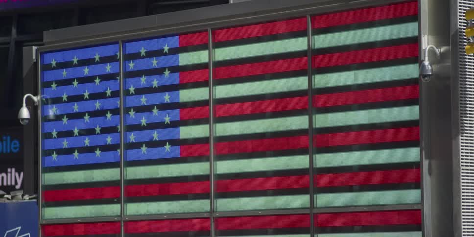 People walk past a large american flag sign