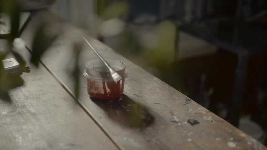 A paint brush sits on top of a small plastic bowl on a table
