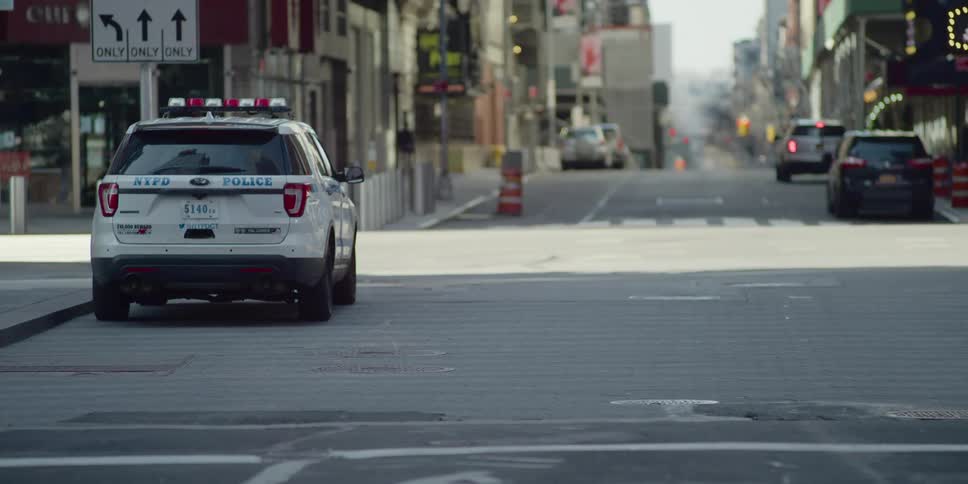 A police vehicle sits at an intersection of passing cars