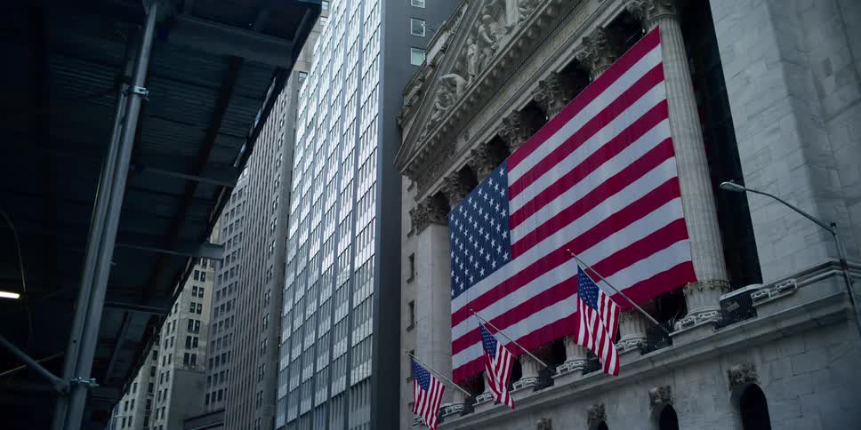 An enormous american flag hangs across the front of the new york stock exchange building
