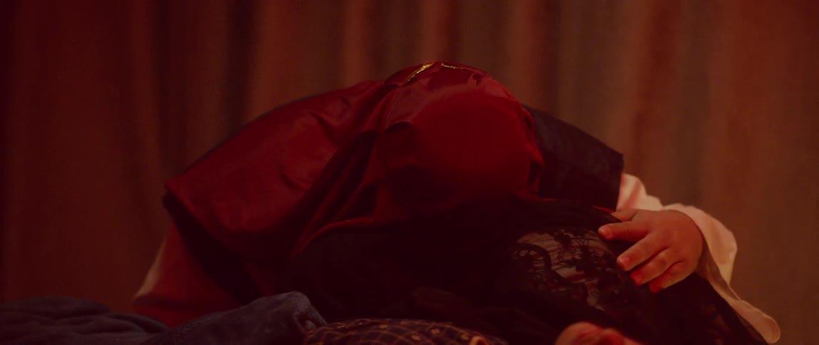 Couple wearing robes embrace while crying over a womans body