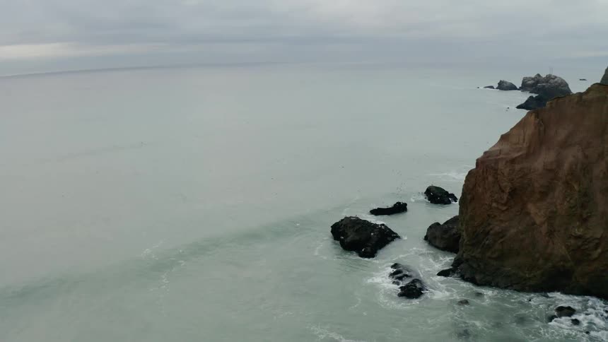 The pale green ocean just off a rocky coast