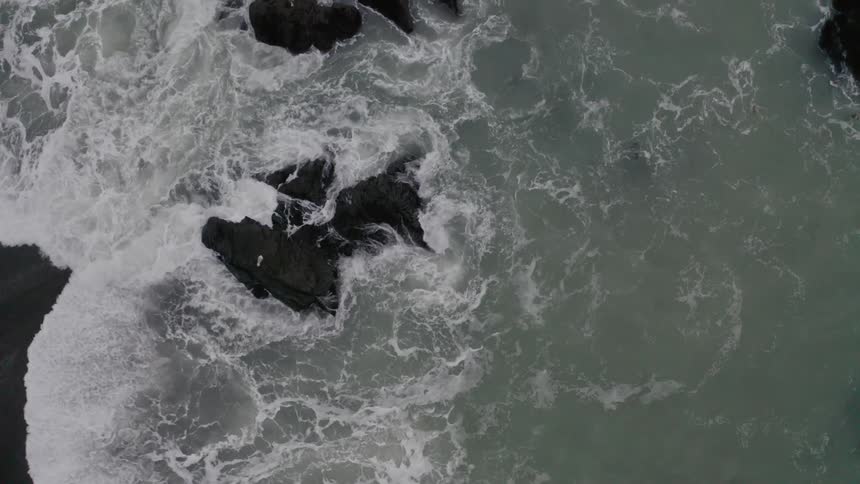 Waves crashing on a rocky shore with birds flying