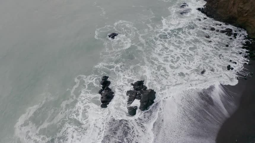 Waves break against the rocks as they come to shore then wash back out