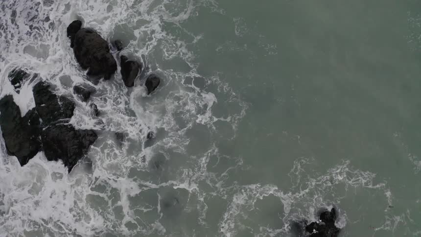 Birds eye view of waves crashing on rocks in the water