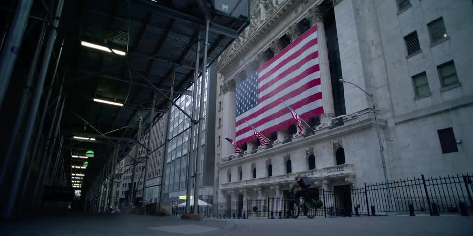 An enormous american flag is hung across the exterior of the new york stock exchange building