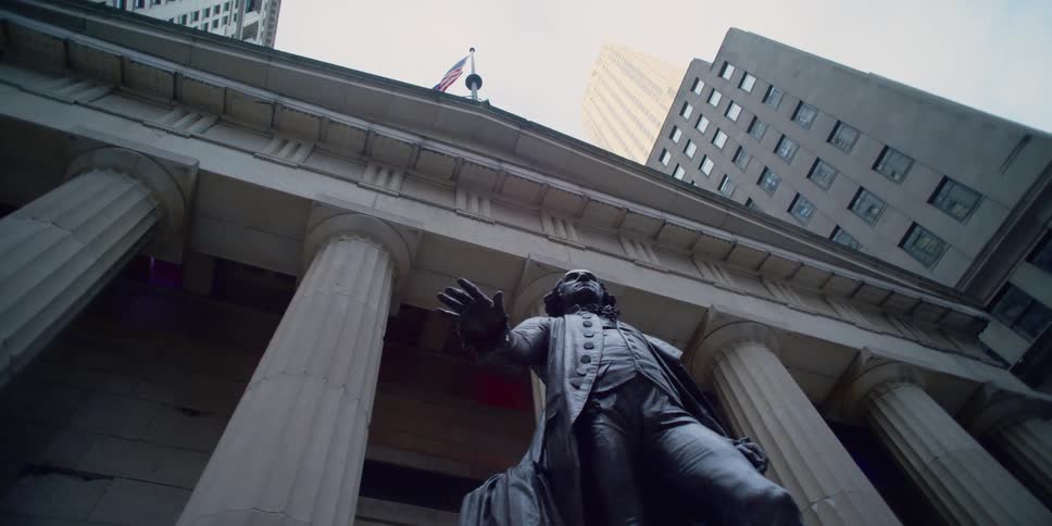 Worms eye view of a statue in front of a building with a flag on top