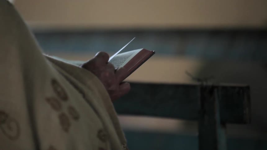A person is sitting down inside reading a book