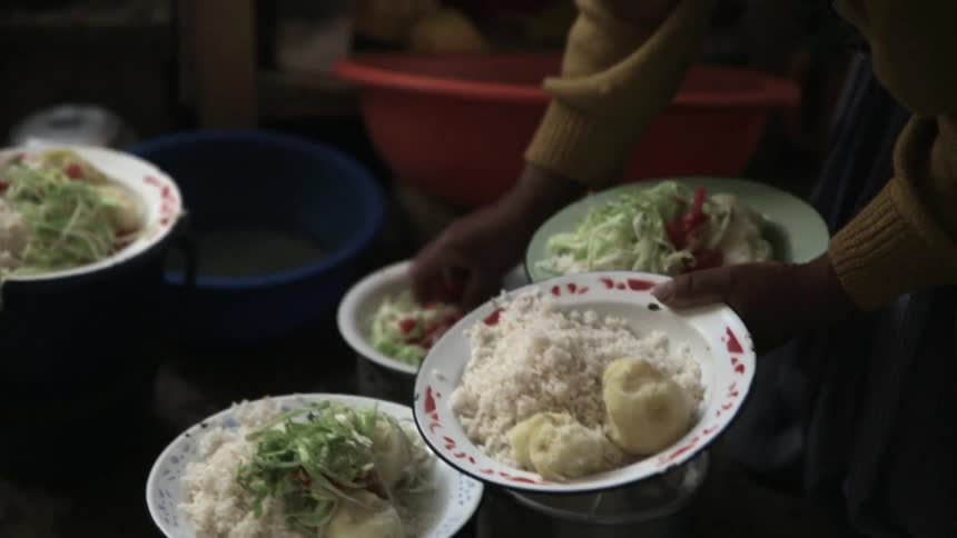 A person grabs a handful of salad from a bowl