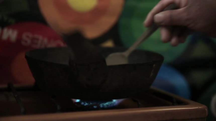 A person is cooking food in a metal pan