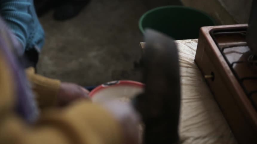 A person pours grain from a pan to a bowl