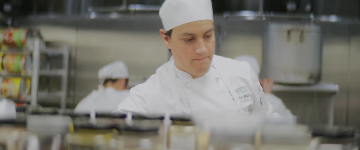 A chef grabs items from a shelf as hes working in a kitchen