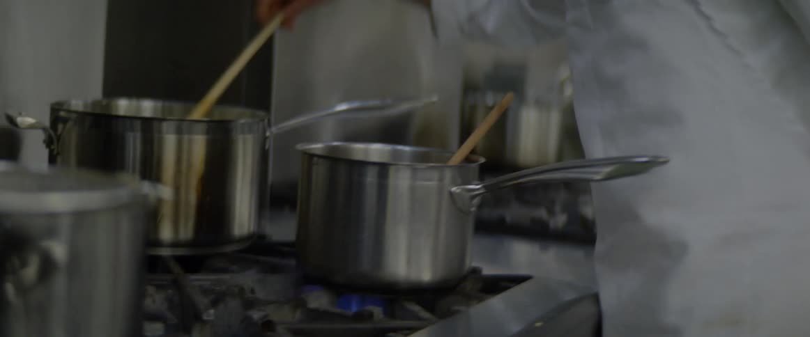 A chef stirs a dish in a pot