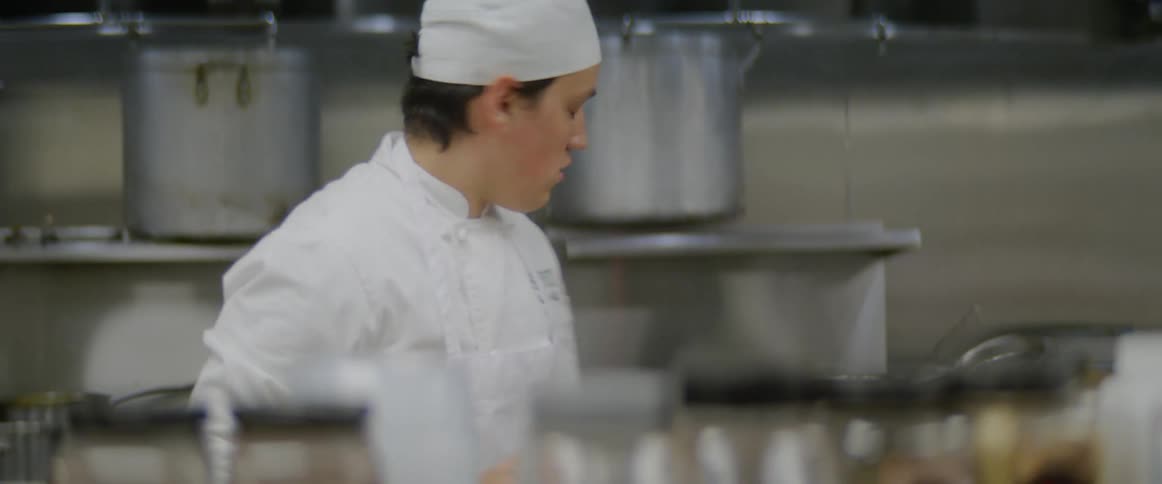 Chef picking up a spice while cooking in the kitchen of a restaurant