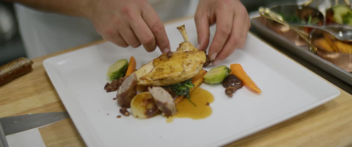 A chef places finishing touches on a dinner plate