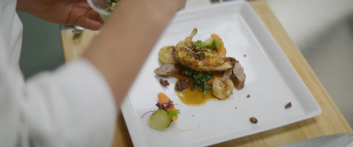 Chef carefully plates meal on square plate