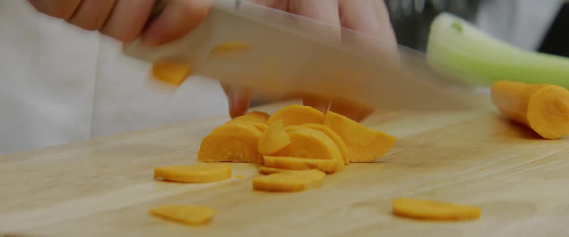 Chef chops carrots on cutting board