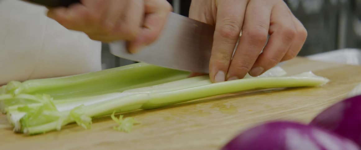 A person is cutting vegetables with a knife