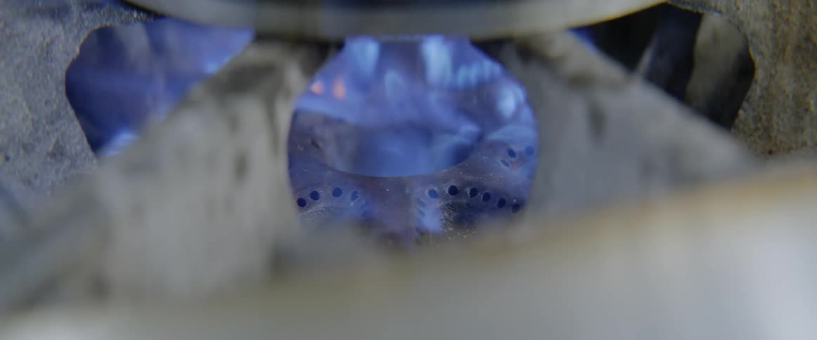 Blue flames are emitted from a gas stove and begin burning