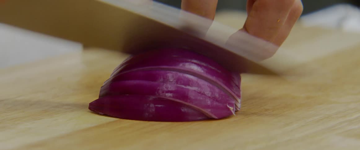 Man chops red onion on the cutting board in the kitchen