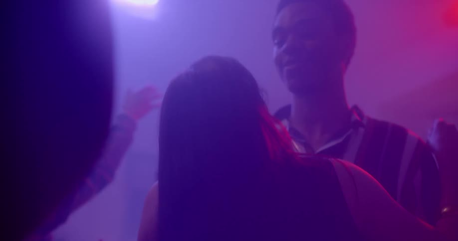 A couple touches and sway as they slow dance at a house party