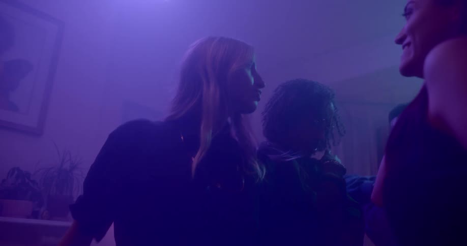 Men and women dance in a darkly lit room