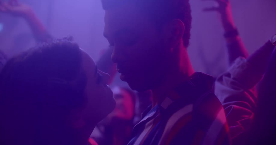 A young woman dances closely with a young male in a crowded club