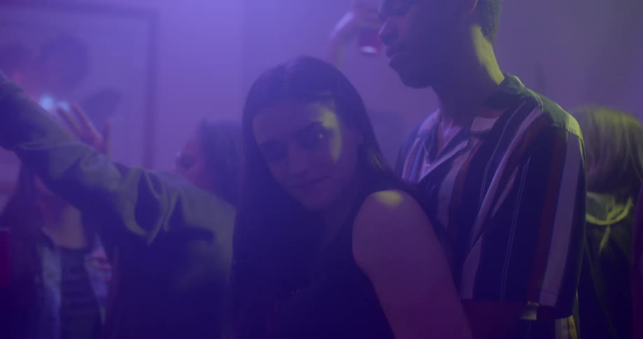 A young woman dances with a young male in a flirtatious manner within a crowded night club