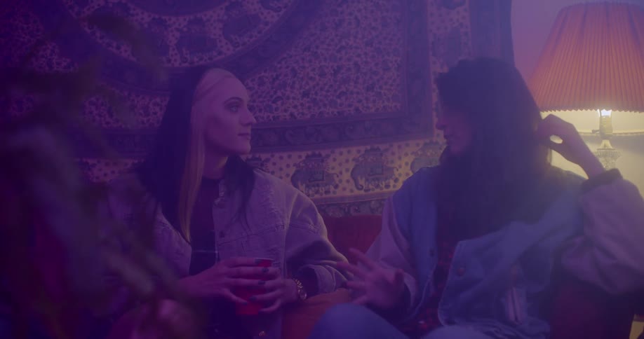 Two woman are sitting on a couch and talking to each other