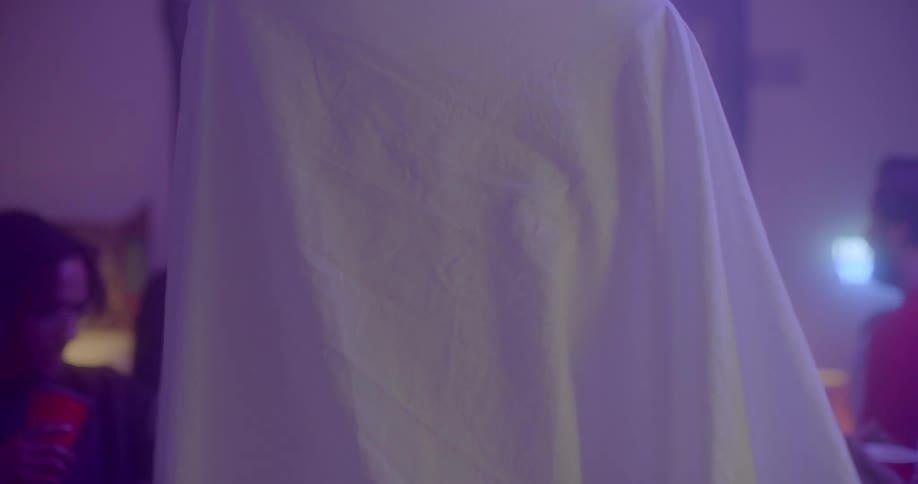 A man standing in front of another person with a sheet over themselves