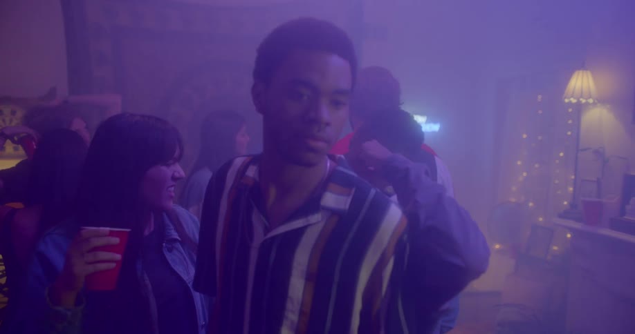 A man walks through dancing people at a party