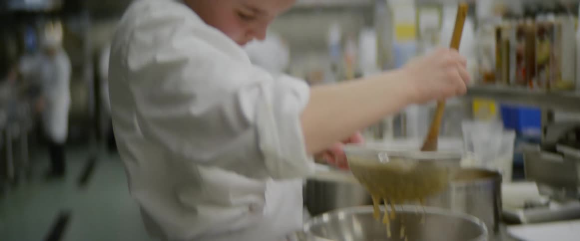 A chef is stirring food in a strainer
