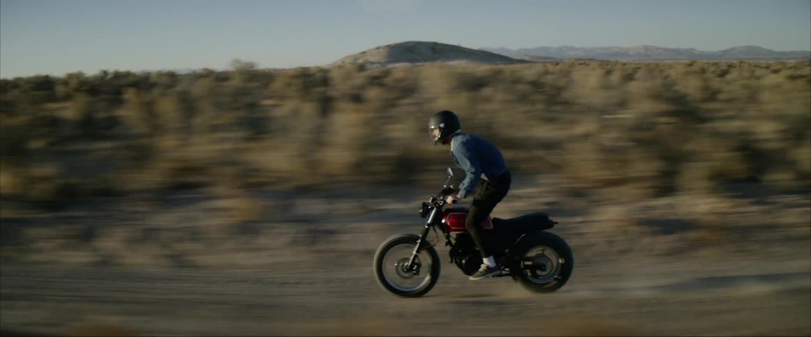A man is riding a motorcycle on a road in a rural area