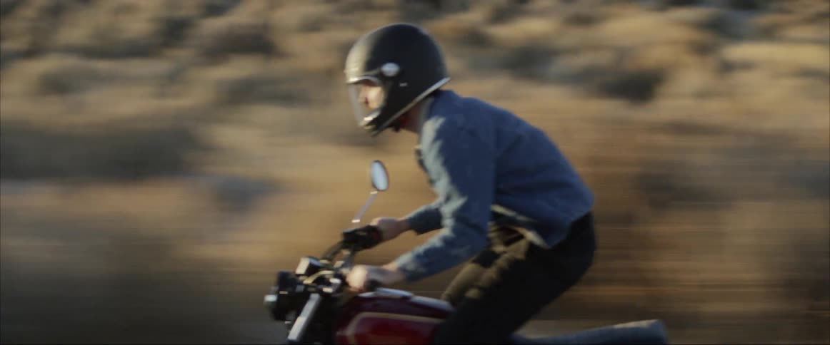 A man is riding a motorcycle in a rural area