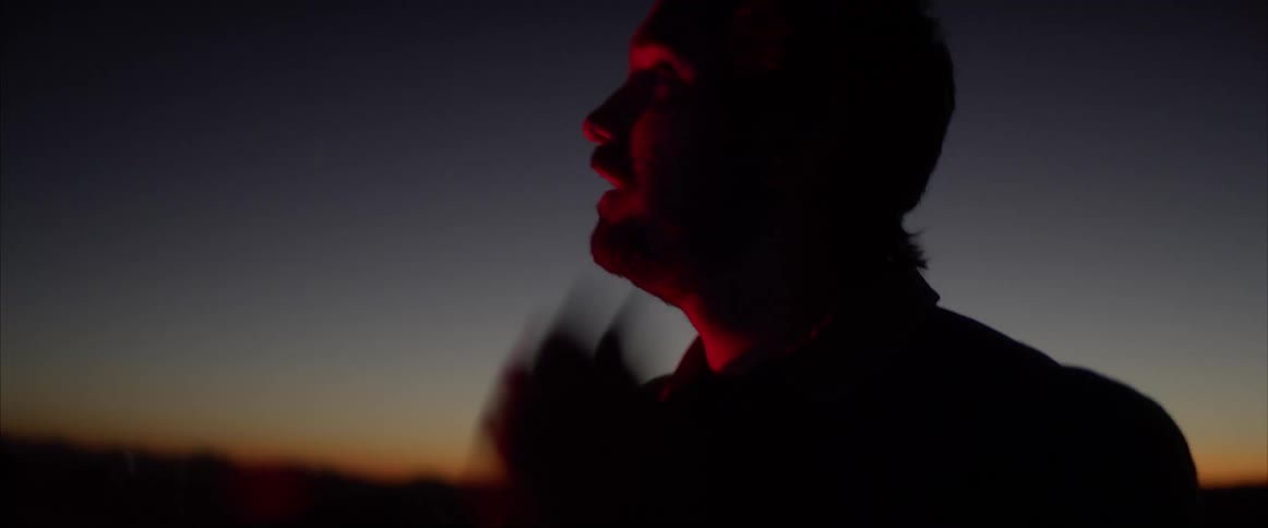 A man taking off his helmet with the sky in the background